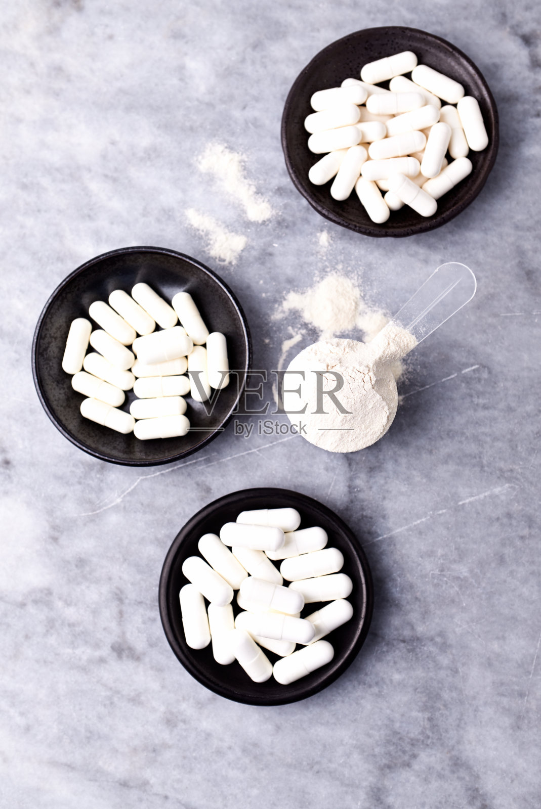 乳清蛋白,水解膠原I型,l -脯氨酸和l -賴氨酸膠囊勺。補充膠原蛋白的生產。明亮的石頭背景。直接上圖。副本的空間。